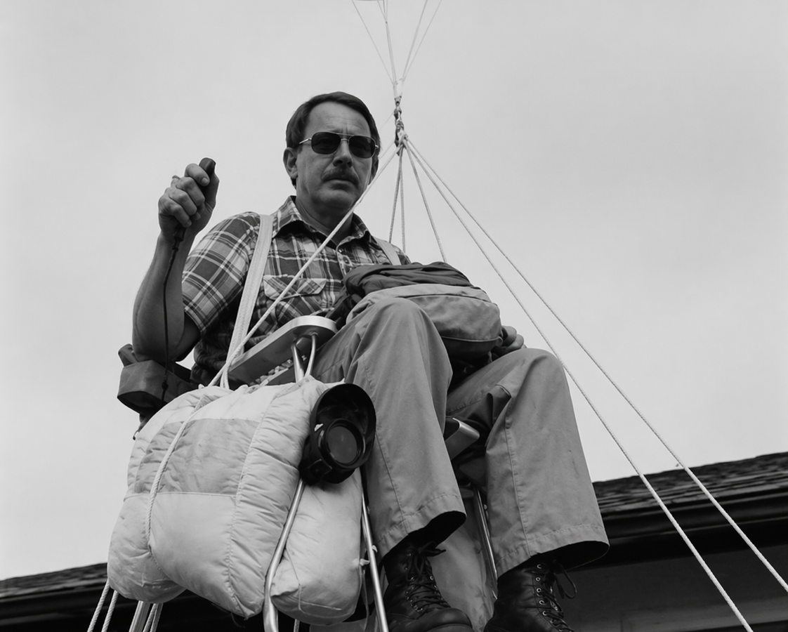 Larry Walters elevándose en una silla de jardín sostenida por globos sobre una casa.