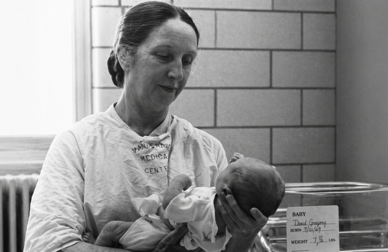Fotografía histórica de Mildred Stahlman sosteniendo a un recién nacido en un entorno hospitalario.