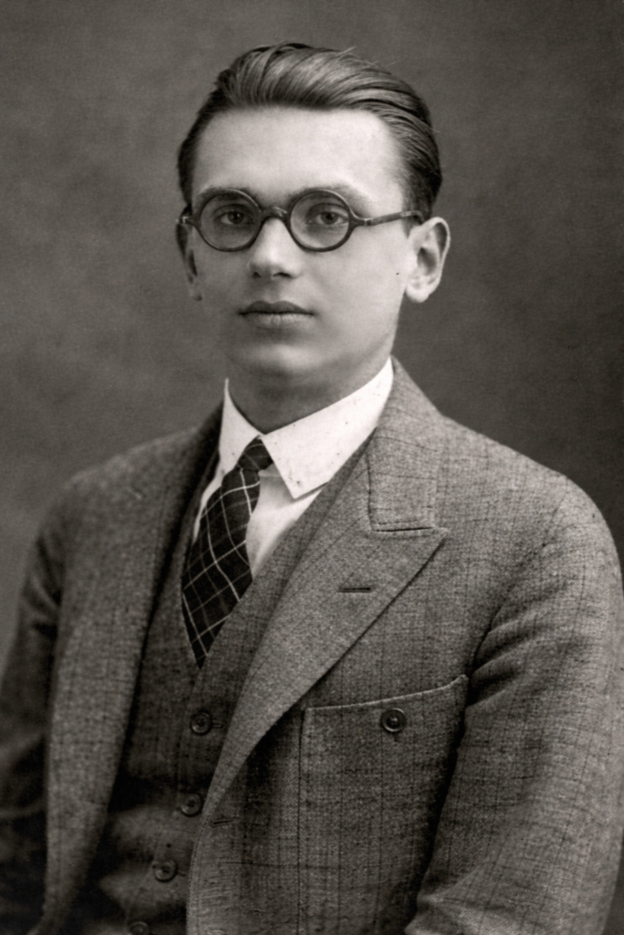 Retrato histórico de un joven con gafas redondas y traje formal, usado para ilustrar la juventud de Kurt Gödel.